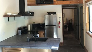 Une cuisine moderne avec un plafond en bois, des appareils électroménagers en acier inoxydable et un coin bar avec des tabourets.