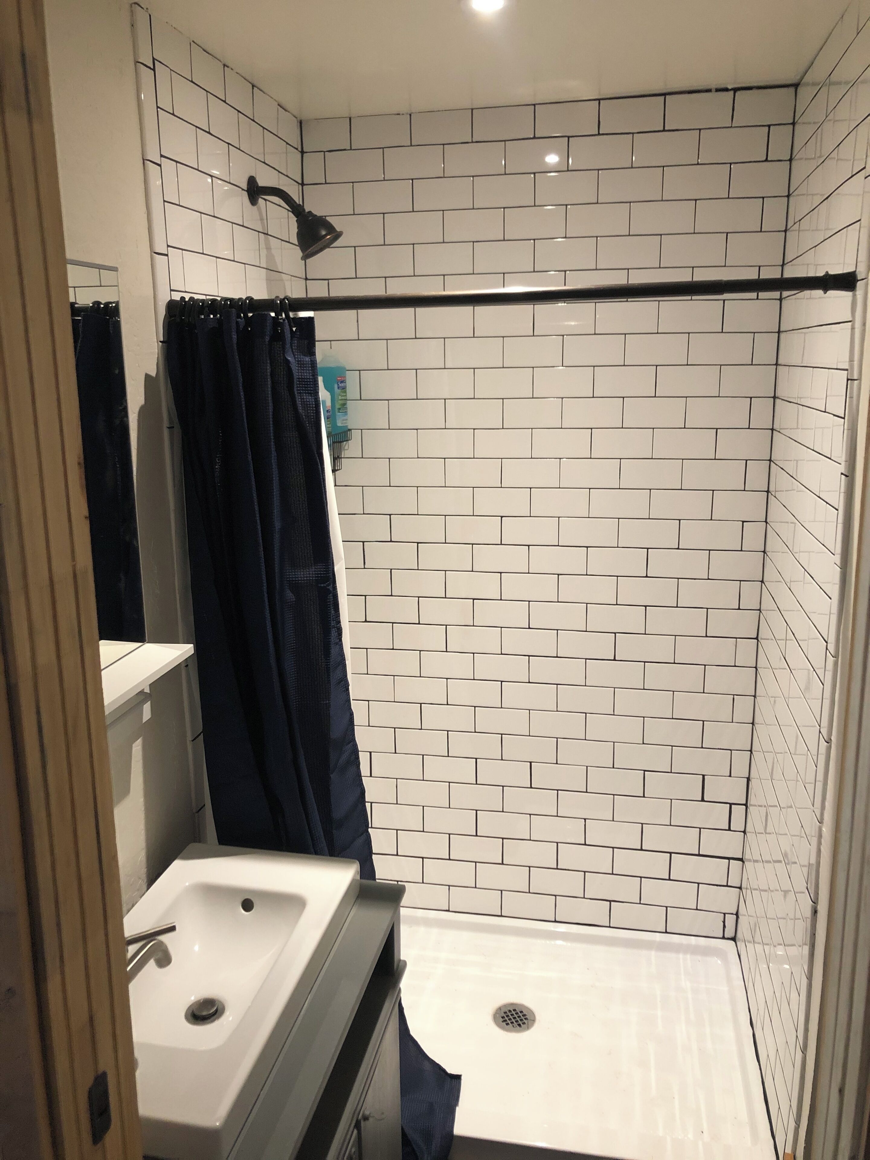 Une salle de bain avec une douche, un lavabo et un miroir.
