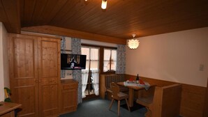 Une cuisine chaleureuse avec des meubles de rangement en bois, une table à manger avec des chaises et un four encastré.