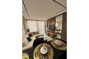 A modern living room with a sofa, a dining table with placemats, and a TV in the background. - Welcome to Twenty Four Inn 202 (Casablanca)