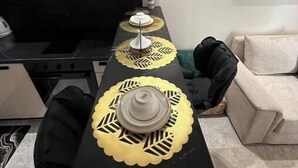 Ein moderner Essbereich mit einem schwarzen Tisch, gelben Untersetzern und einer weißen Tischdekoration.