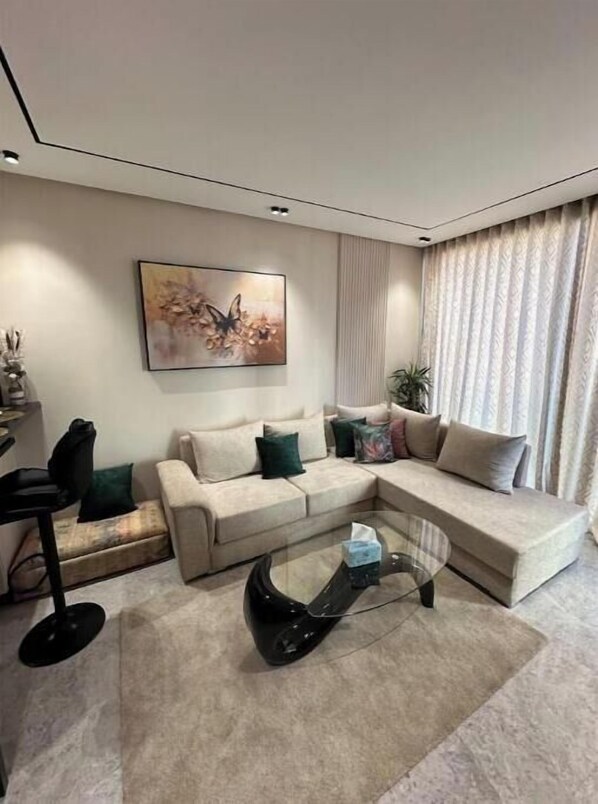 A modern living room with a sectional sofa, a glass coffee table, and a wall-mounted painting.