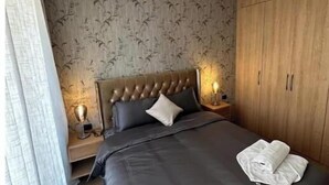 Ein Hotelzimmer mit einem großen Bett, einem Holzschrank und einem Nachttisch mit einer Lampe.