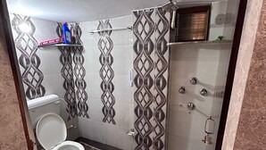 Et badeværelse med toilet, brusebad og mønstrede fliser.