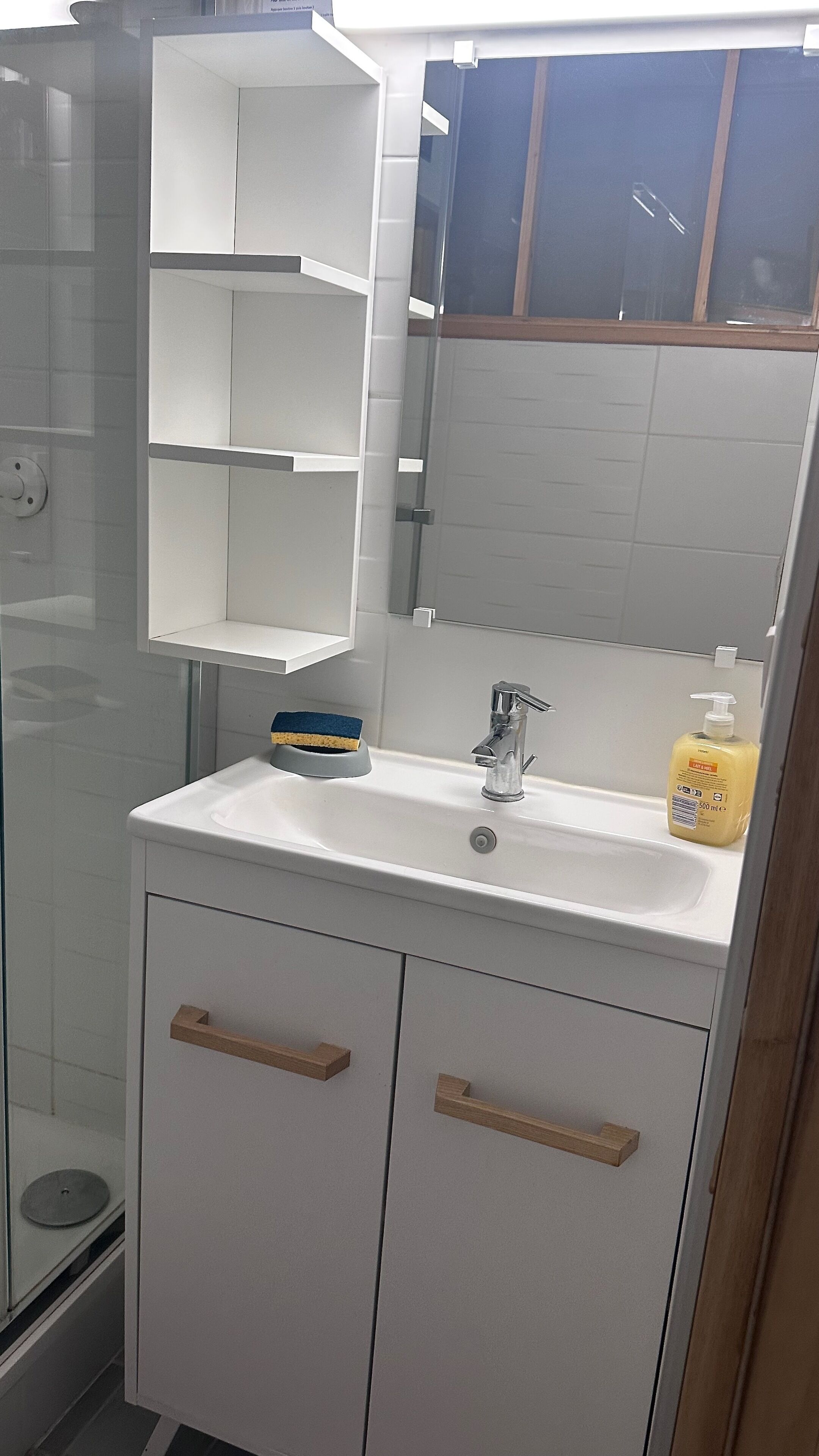 A bathroom with a white sink, a mirror, and a shower enclosure.