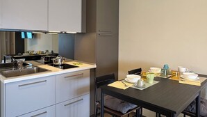 A modern kitchen with white cabinets, a black countertop, and a dining area with a black table and chairs. - Sulmare Studios - Molocali Sea View (Alba Adriatica)