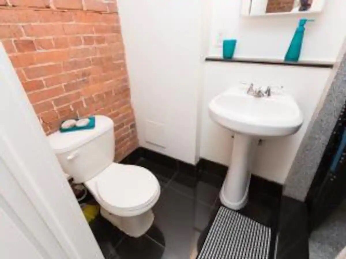 Une petite salle de bain avec des toilettes blanches, un lavabo blanc et un sol carrelé.