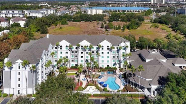 A multi-story hotel with a swimming pool and landscaped grounds. - Inspiration condo near Disney with free shuttle (Orlando)