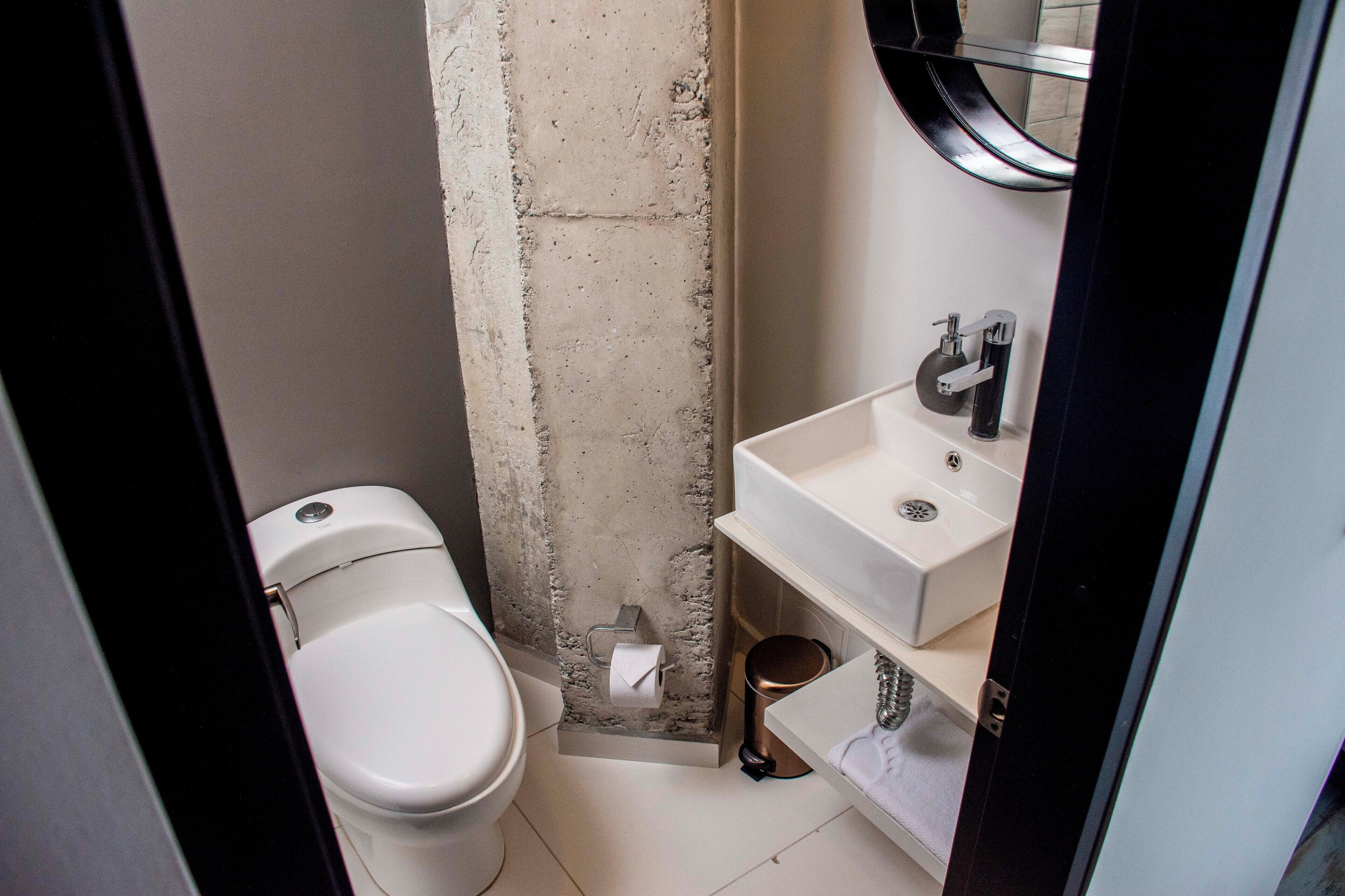 Une petite salle de bain avec des toilettes, un lavabo et un miroir.