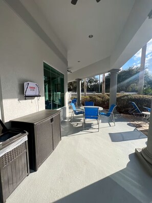 An outdoor patio with a grill, blue chairs, and a charging station.