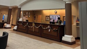 A hotel lobby with a reception desk, large wall art, and a clock. - Renovated Condo near Disney Free Shuttle to Parks (Orlando)