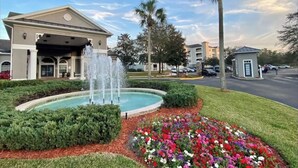 A hotel with a fountain, landscaped garden, and palm trees. - Amazing Condo near Disney World (Kissimmee)
