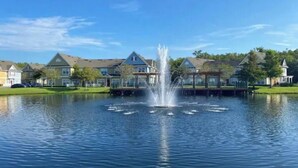 Zona residencial con casas, una fuente central y un lago tranquilo.