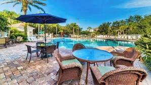 Un espace aménagé au bord de la piscine, avec des meubles en osier et un grand parasol.