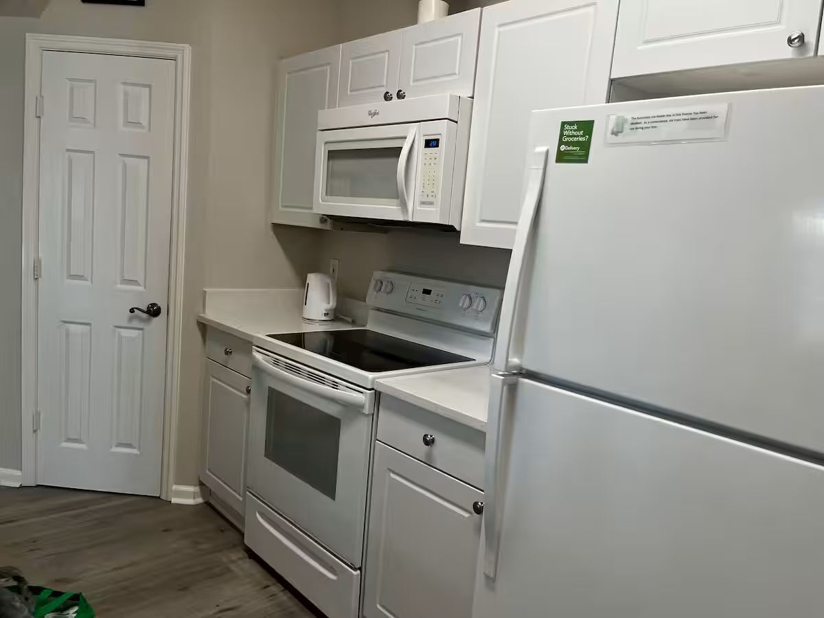 A kitchen with white cabinetry, a microwave, stove, oven, and a refrigerator.
