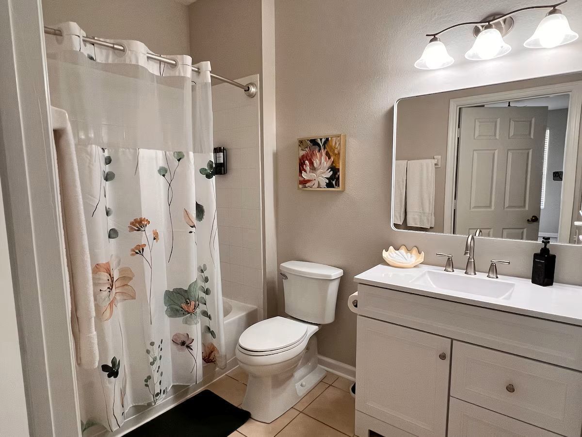Un baño con cortina de ducha, inodoro, lavabo y espejo.