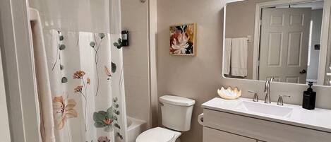Un baño con cortina de ducha, inodoro, lavabo y espejo.
