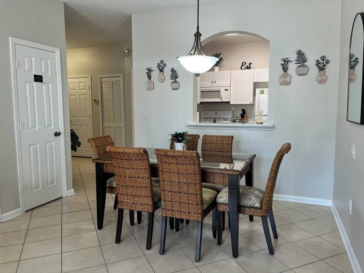 A dining area with wicker chairs, a table, and a hanging light fixture.