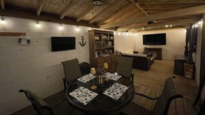 A cozy, rustic dining area with a round table, chairs, and a wooden ceiling. - Limestone Landing - Pool, firepit, covered patio, & more! (Kelleys Island)