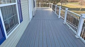 A wooden deck with a white railing and a window with blue shutters. - Limestone Landing - Pool, firepit, covered patio, & more! (Kelleys Island)