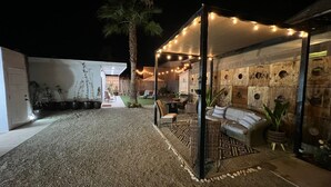 An outdoor patio area with a seating arrangement, string lights, and a palm tree. - House in rosarito beaches 7 (Playas de Rosarito)