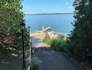 A pathway leading to a beach with a lamp post and a wooden dock extending into the water.