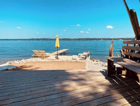 A wooden deck with a bench, a table, and a yellow umbrella.