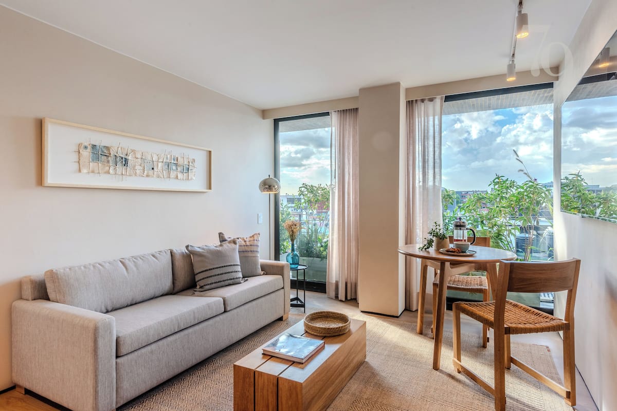 A modern living room with a sofa, coffee table, and dining area with chairs and a table.