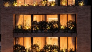 Un edificio con varios balcones, cada uno adornado con plantas e iluminación cálida.