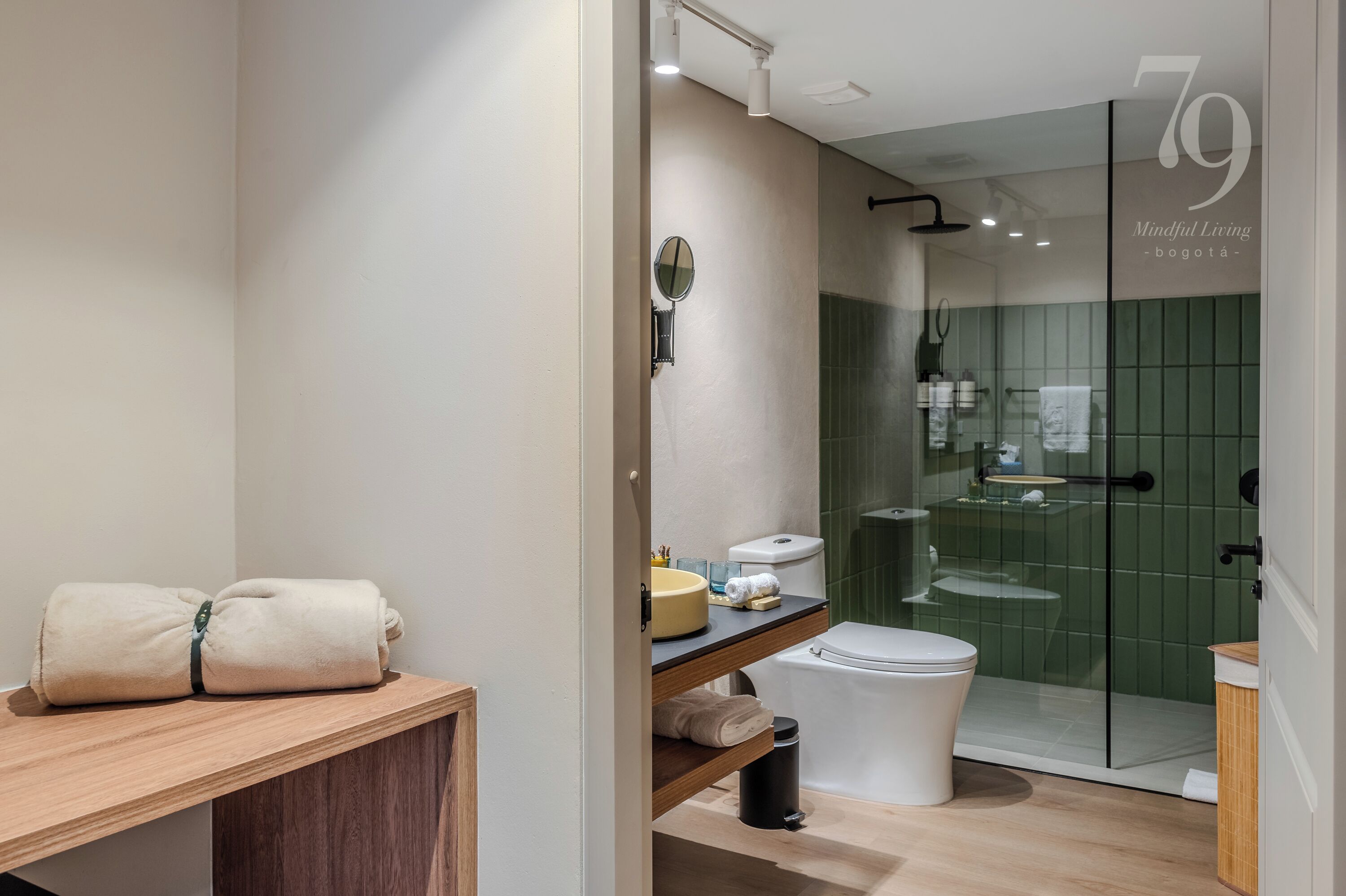 A modern bathroom with a glass shower enclosure, a toilet, a sink with a mirror, and a wooden shelf with towels.