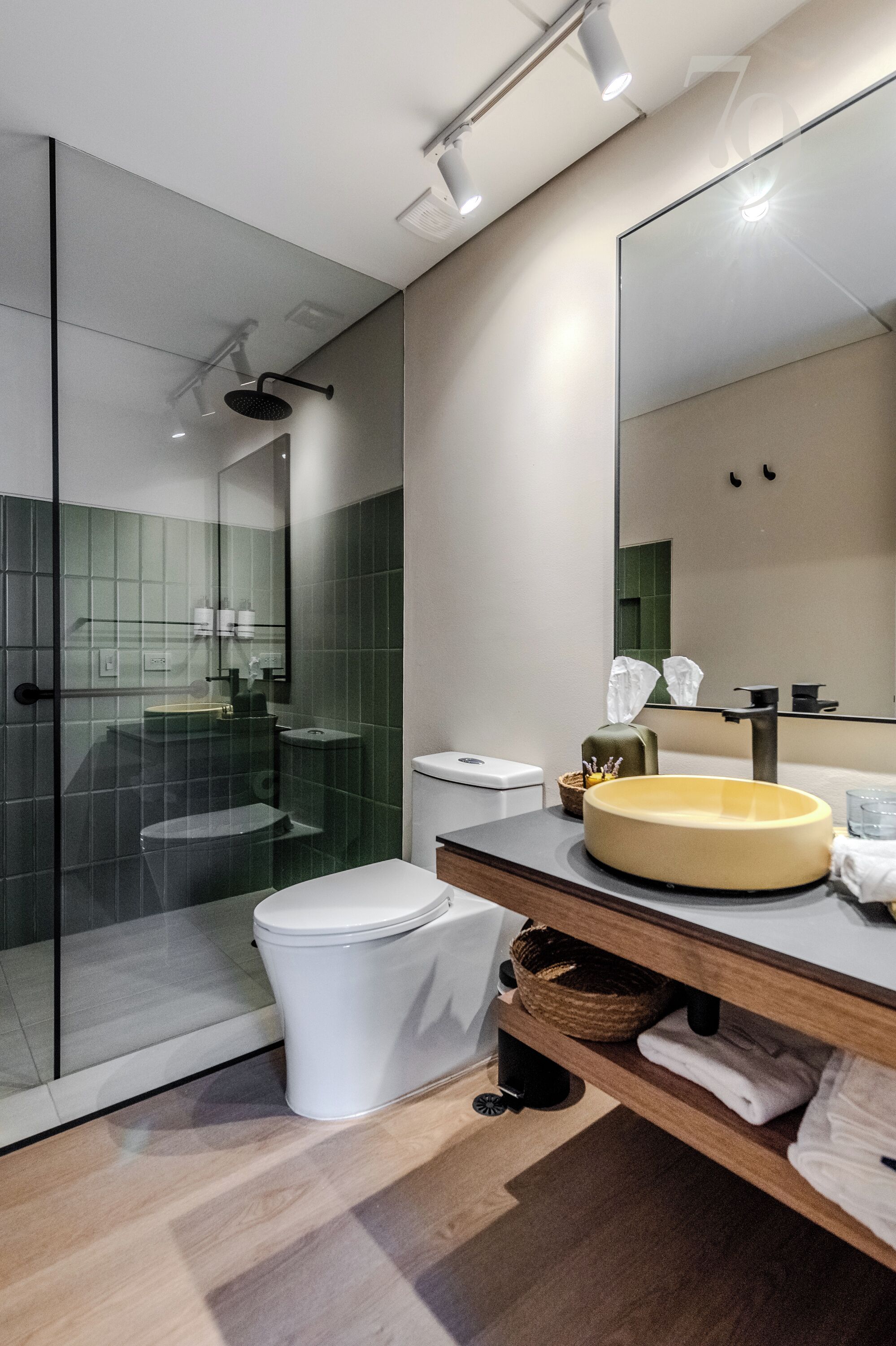 Une salle de bain moderne avec une douche à parois de verre, des toilettes blanches, un grand miroir et un meuble-lavabo en bois.