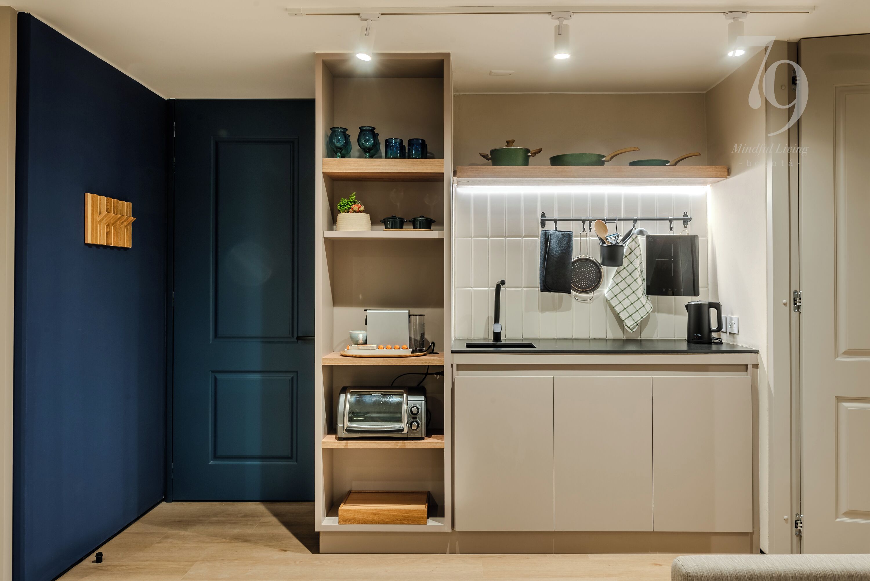 A compact kitchen with built-in shelves, a microwave, and a kettle.