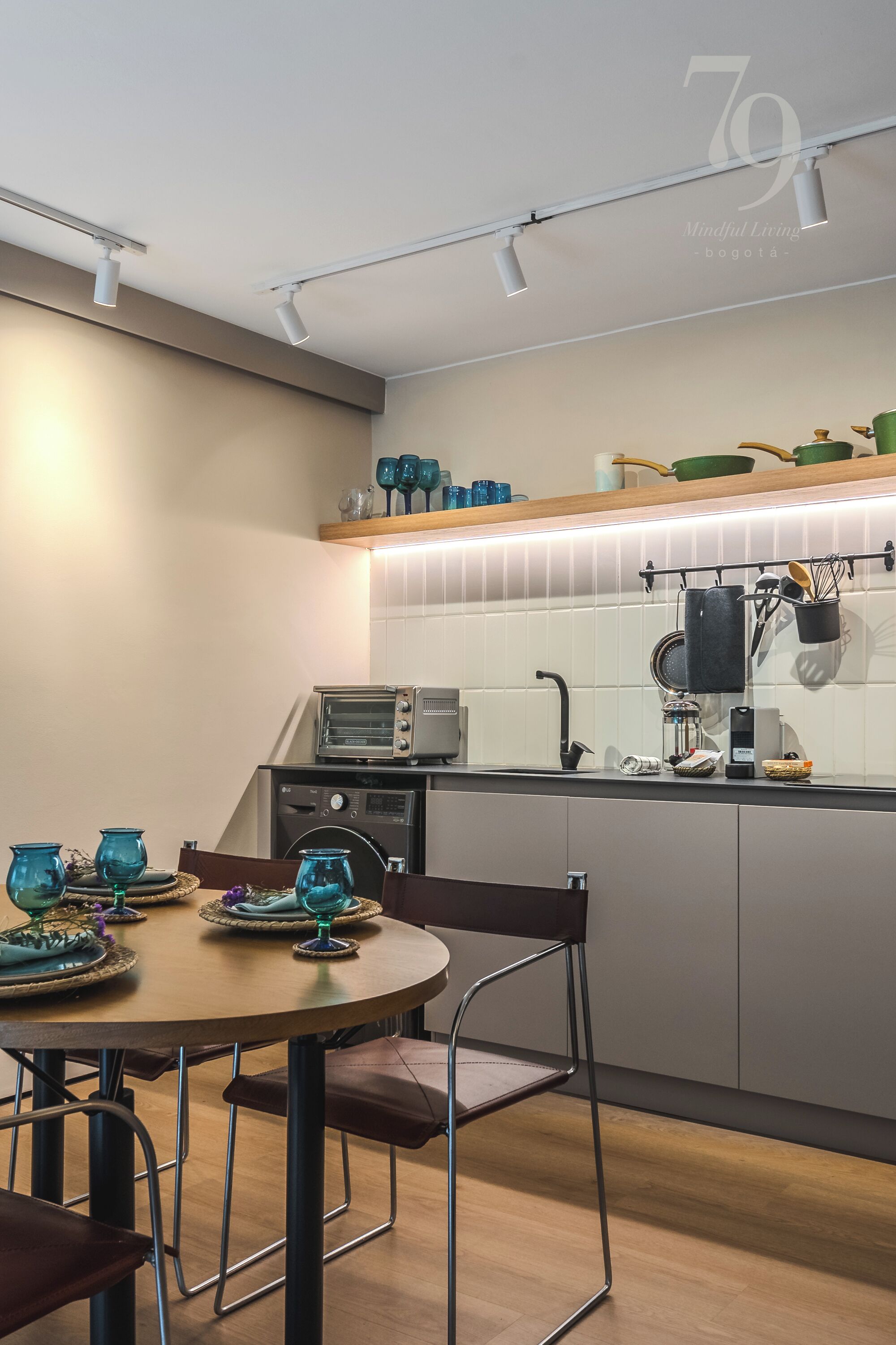 A modern kitchen with a dining area, featuring a round table, chairs, and a countertop with various kitchen appliances and utensils.