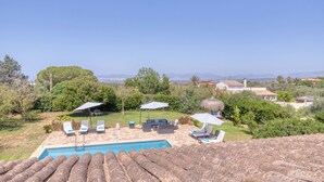 A pool area with lounge chairs and umbrellas, surrounded by greenery and a view of distant mountains. - Villa Kentia Mallorca, stylish country house close to Palma (Palma)