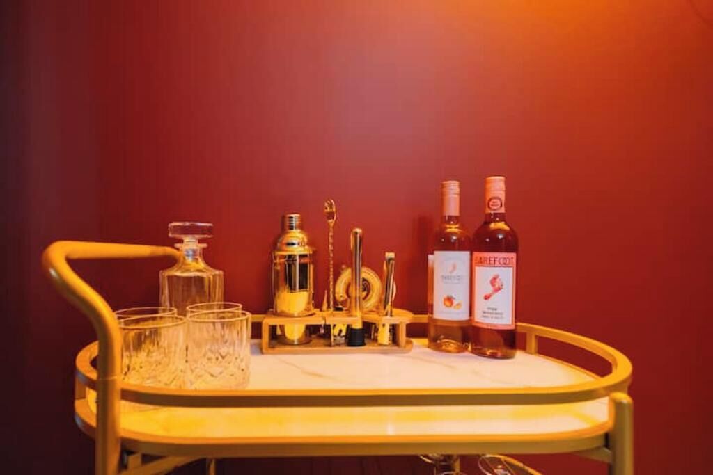 Un chariot à boissons avec des verres, une bouteille de vin Barefoot et une bouteille d’eau.