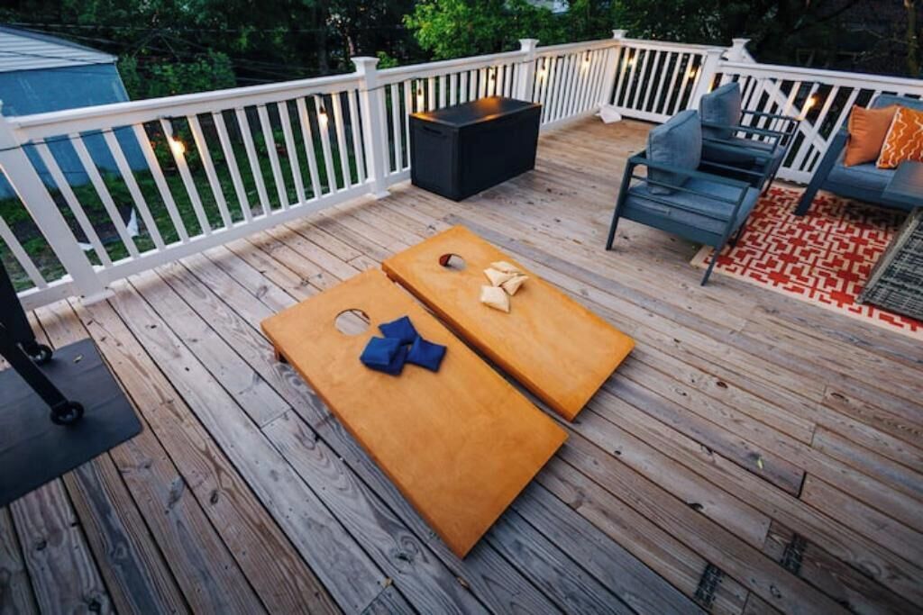 A wooden deck with two bean bag chairs and a small table, surrounded by a white railing.