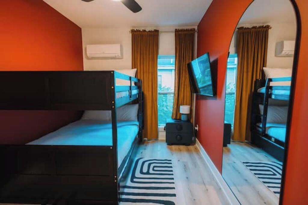 A room with bunk beds, a television, and a window with curtains.