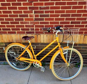 A yellow bicycle parked against a brick wall.