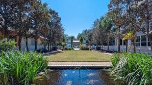 Un espace paysager agrémenté d’un élément aquatique central, entouré d’arbres et bordé d’une allée pavée.