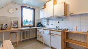 Una cucina compatta con finestra, bollitore, macchina del caffè e lavandino.