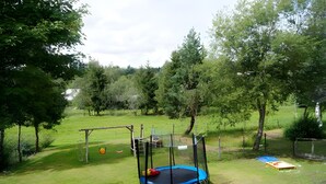 A grassy outdoor area with a trampoline, swing set, and a small play structure.