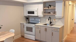 A compact kitchen with white cabinetry, a microwave, a stove, and a sink.