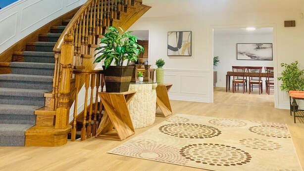 Una escalera con barandas de madera que lleva a un comedor con una mesa y sillas.