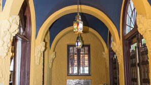 Un pasillo con arcos, suelo de baldosas estampadas y un farol colgante.