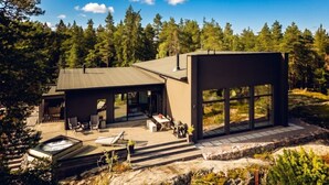Une maison moderne dotée d’une terrasse, d’un espace salon extérieur et d’un jacuzzi.