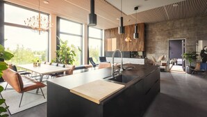 Une cuisine moderne dotée d’un grand îlot central, d’appareils électroménagers intégrés et d’un coin repas avec une table et des chaises.
