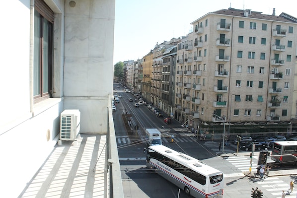 A multi-story building with balconies, a street with vehicles, and a tram.