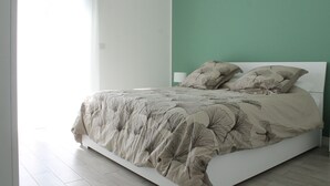 A bed with a floral bedspread and two pillows, a white headboard, and a green wall. - Central Stay, Cozy Way (Milano)