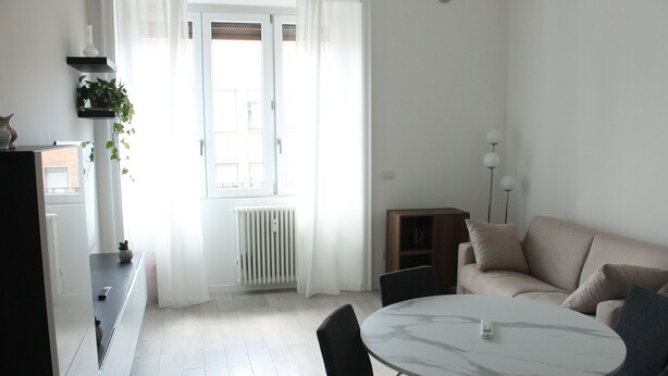 A modern living room with a round marble table, a beige sofa, and a small cabinet. - Central Stay, Cozy Way (Milano)