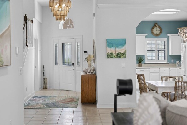 A spacious living area with a dining table, a sofa, and a kitchen in the background. - Stunning 3 BR 3 BA luxury beach home in St. Augustine, FL (Saint Augustine)